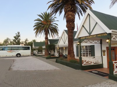 Okiep Country Hotel met palmbomen en touringcar tijdens route Kaapstad - Victoria Falls.