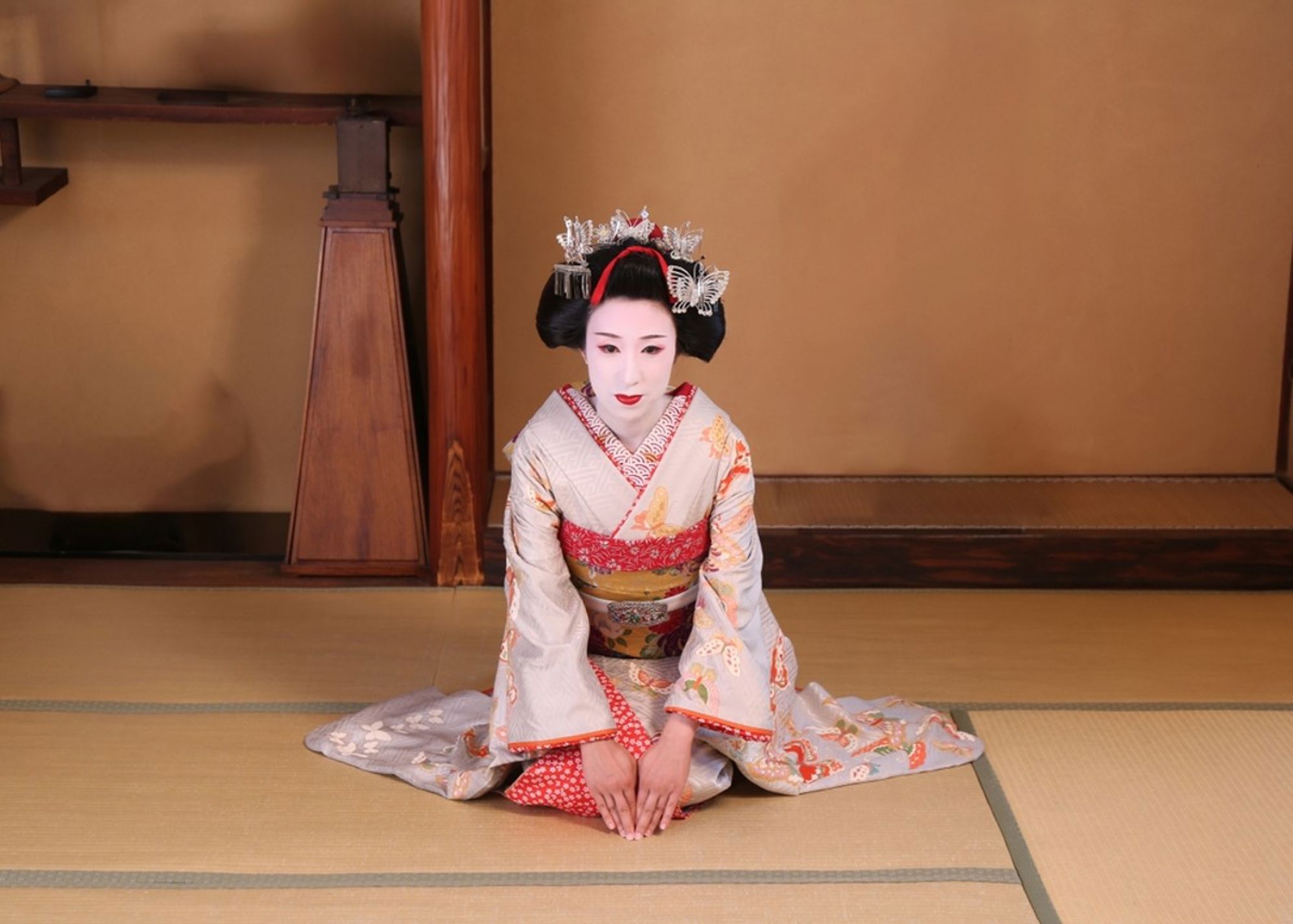 Geisha in traditionele kimono knielt op tatamimat in een Japans theehuis.