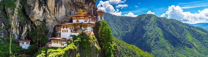 Tijgersnest-klooster in Bhutan, gebouwd tegen een steile rotswand met uitzicht op groene bergen.