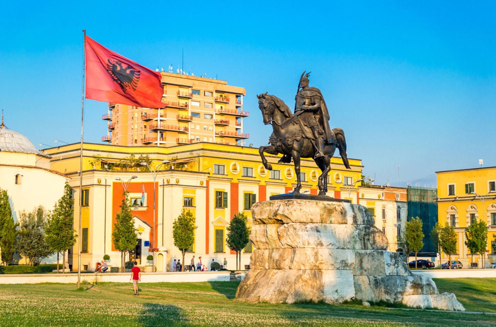 Standbeeld van Skanderbeg op het Skanderbegplein in Tirana, met de Albanese vlag op de achtergrond.