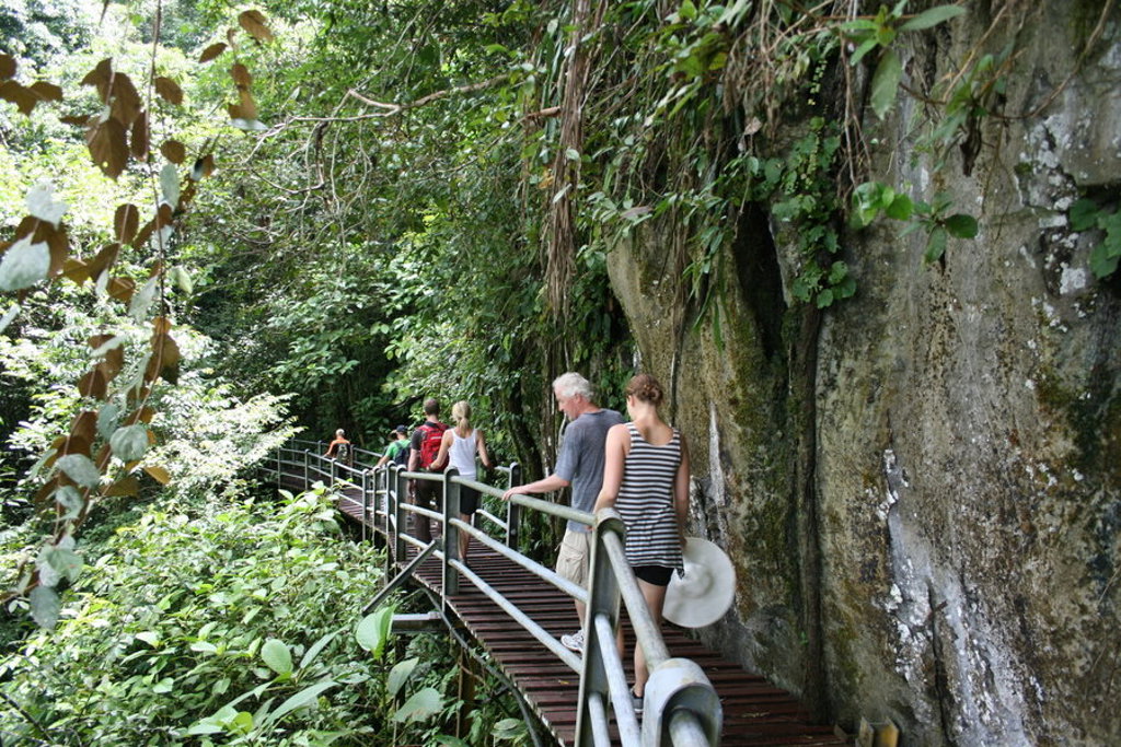 Gezin wandelt over een jungleloopbrug langs rotswand in Maleisisch Borneo.