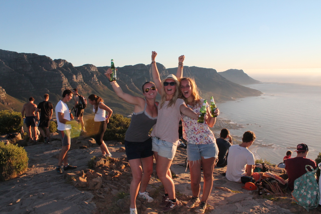 Vrienden proosten bij zonsondergang op Lion’s Head met uitzicht op Kaapstad, tijdens 22-35ers reis Zuid-Afrika.