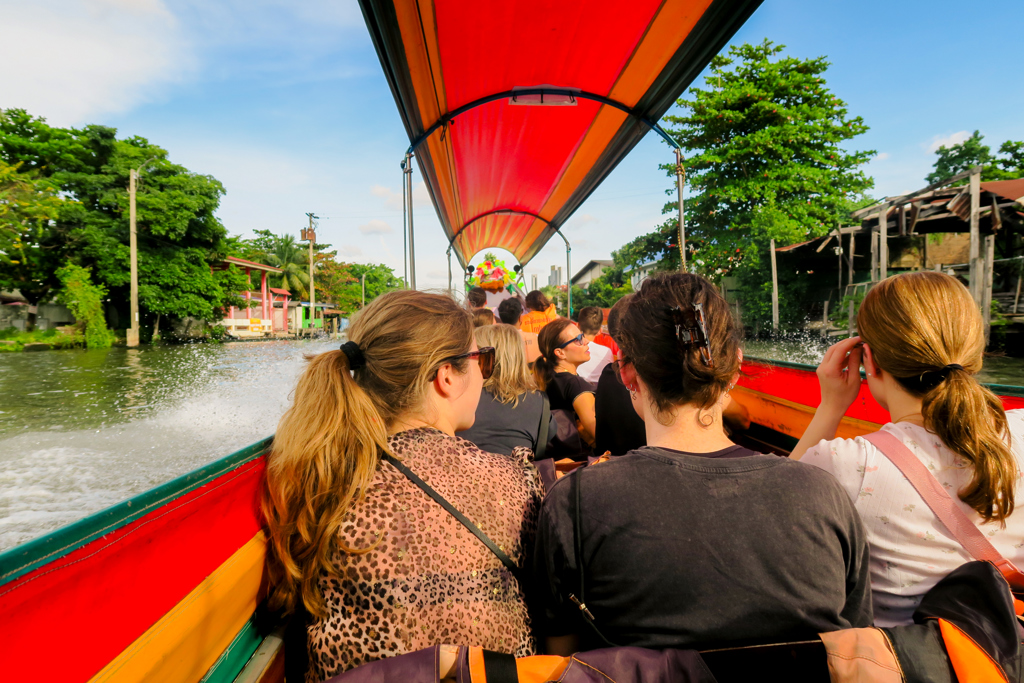 22-35ers reizen per longtailboot over een kanaal in Thailand, Laos en Cambodja.