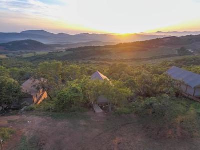 Safari-lodges tussen groen heuvelgebied bij zonsondergang in Zuid-Afrika.