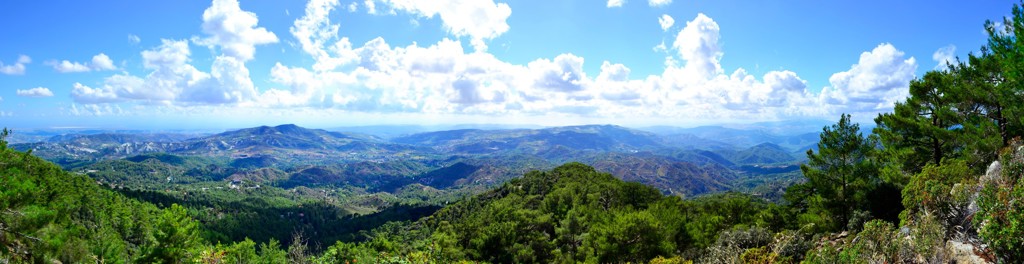 Panoramisch uitzicht over de groene Troodosbergen op Cyprus onder een blauwe lucht met wolken.