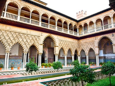 Binnenplaats met Moorse bogen, sierlijke details en waterbassin in het Real Alcázar van Sevilla, Andalusië.