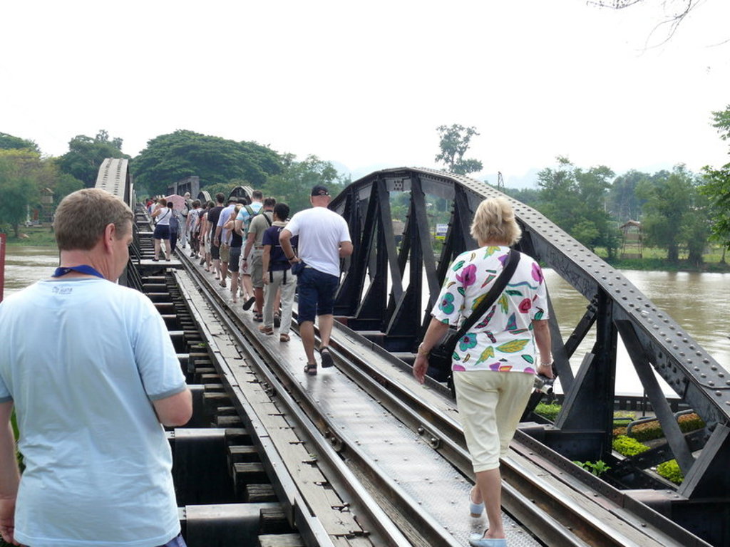 Reizigers lopen over de brug over de River Kwai bij Kanchanaburi tijdens een groepsrondreis Thailand.