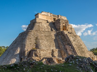 Piramide van Uxmal in Mexico, met stenen trappen en tempel tegen een heldere blauwe lucht.