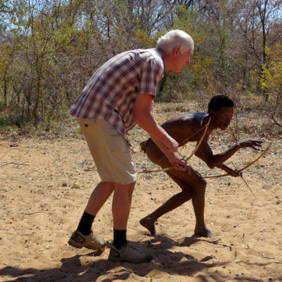 Reiziger oefent boogschieten met lokale gids tijdens groepsrondreis Namibië.