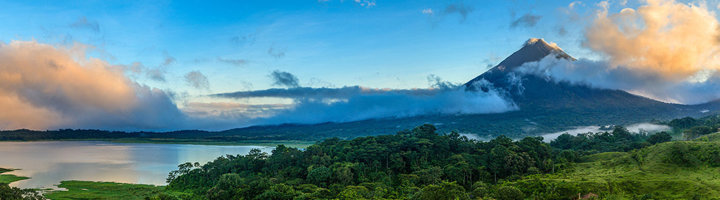Arenal-vulkaan bij zonsopkomst met nevel boven het regenwoud en het Arenalmeer in Costa Rica.