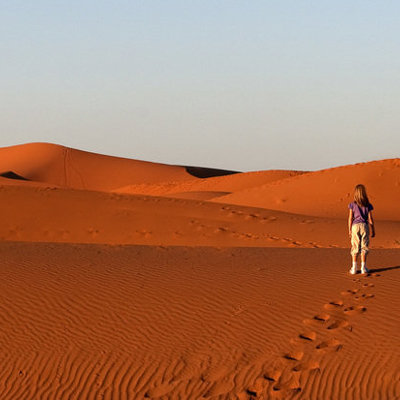 Kind wandelt door de zandduinen van de Sahara in Marokko tijdens een familiereis.