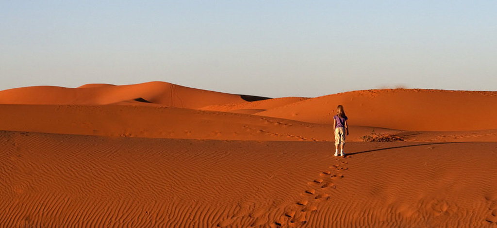 Kind wandelt door de zandduinen van de Sahara in Marokko tijdens een familiereis.