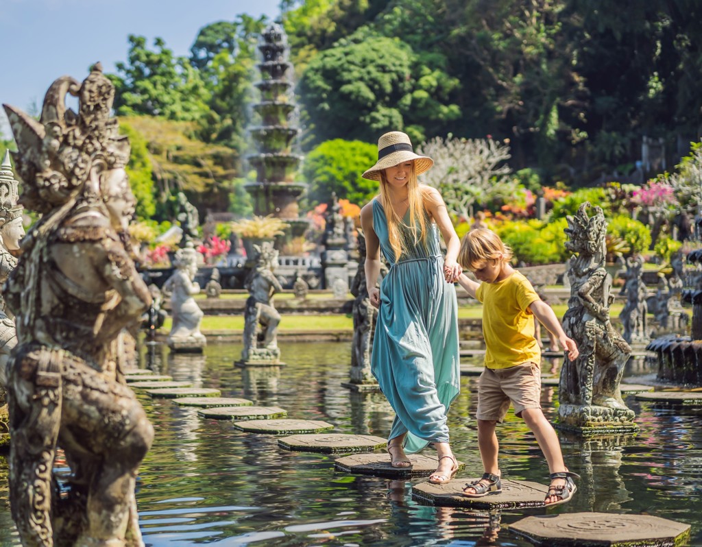 Moeder en kind lopen over stapstenen in het waterpaleis Tirta Gangga op Bali tijdens familiereis Java en Bali.