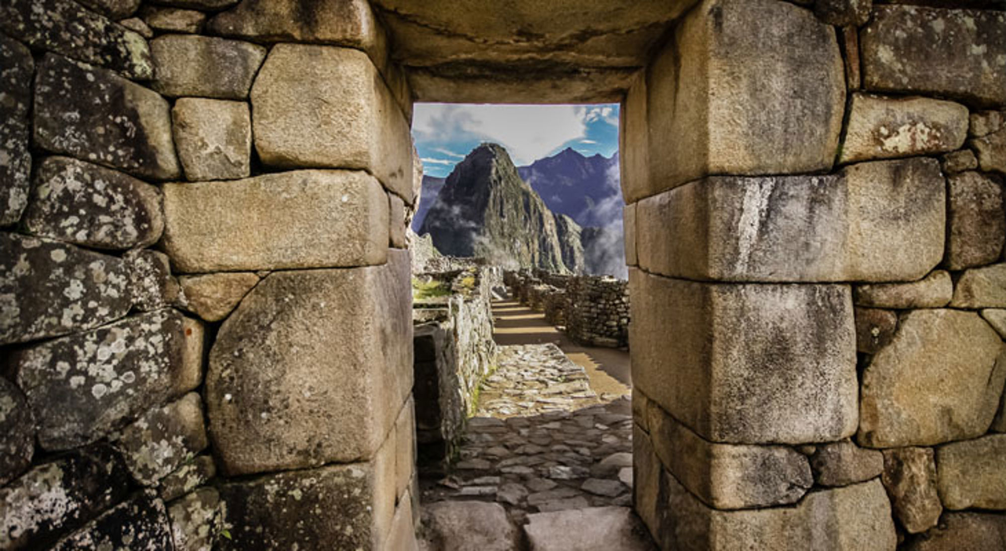 Doorkijk door stenen poort naar Machu Picchu met de Huayna Picchu-berg op de achtergrond, Peru.