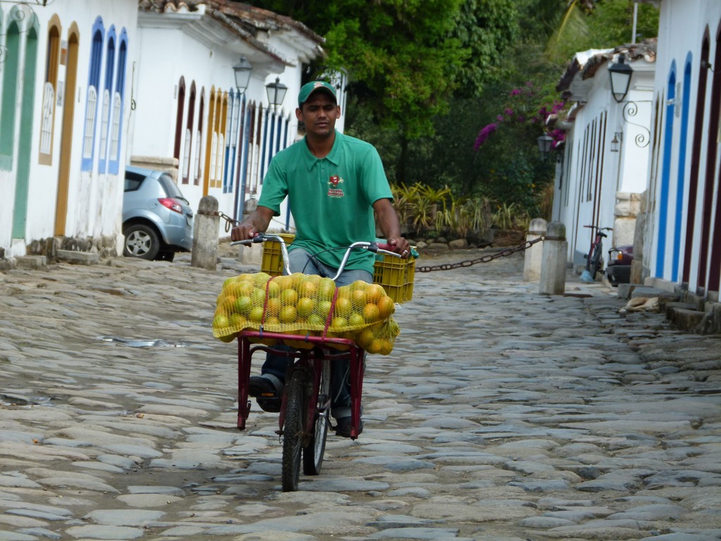 Fietser met manden vol citrusvruchten in een historische straat in Brazilië tijdens groepsrondreis Brazilië en Buenos Aires.