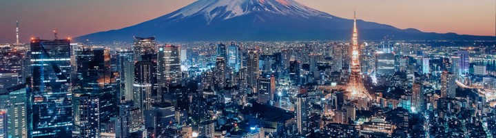 Mount Fuji met besneeuwde top boven de skyline van Tokio bij schemering.