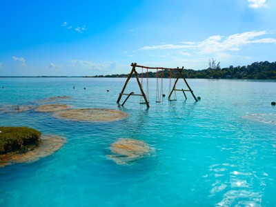 Houten schommel in het heldere water van Bacalar Lagoon tijdens de Route Mexico.