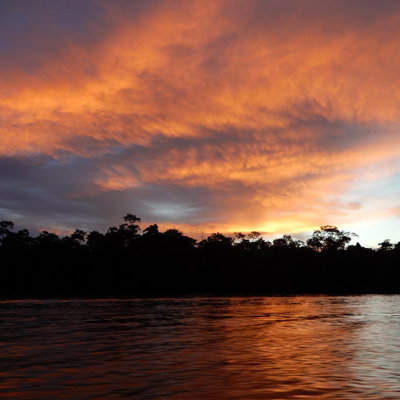 Zonsondergang boven een rivier in Maleisisch Borneo, met silhouetten van regenwoud langs de oever.