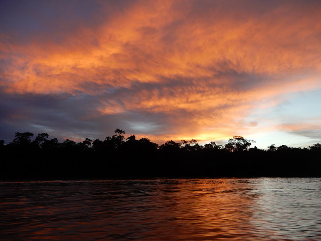 Zonsondergang boven een rivier in Maleisisch Borneo, met silhouetten van regenwoud langs de oever.