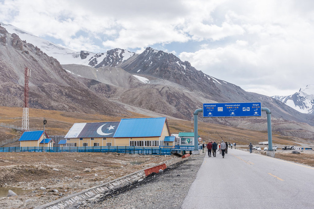 Weg in Baltistan, Pakistan met berglandschap, gebouw met Pakistaanse vlag en wegwijzer naar Gilgit.