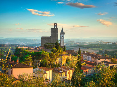 Toscaans heuvellandschap met middeleeuws dorp en kerktoren bij zonsondergang.