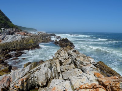 Rotsachtige kustlijn met beukende golven langs de Garden Route tussen Johannesburg en Kaapstad.