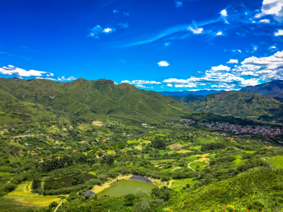 Groene bergvallei met dorpjes en akkers onder een helderblauwe lucht in Ecuador.