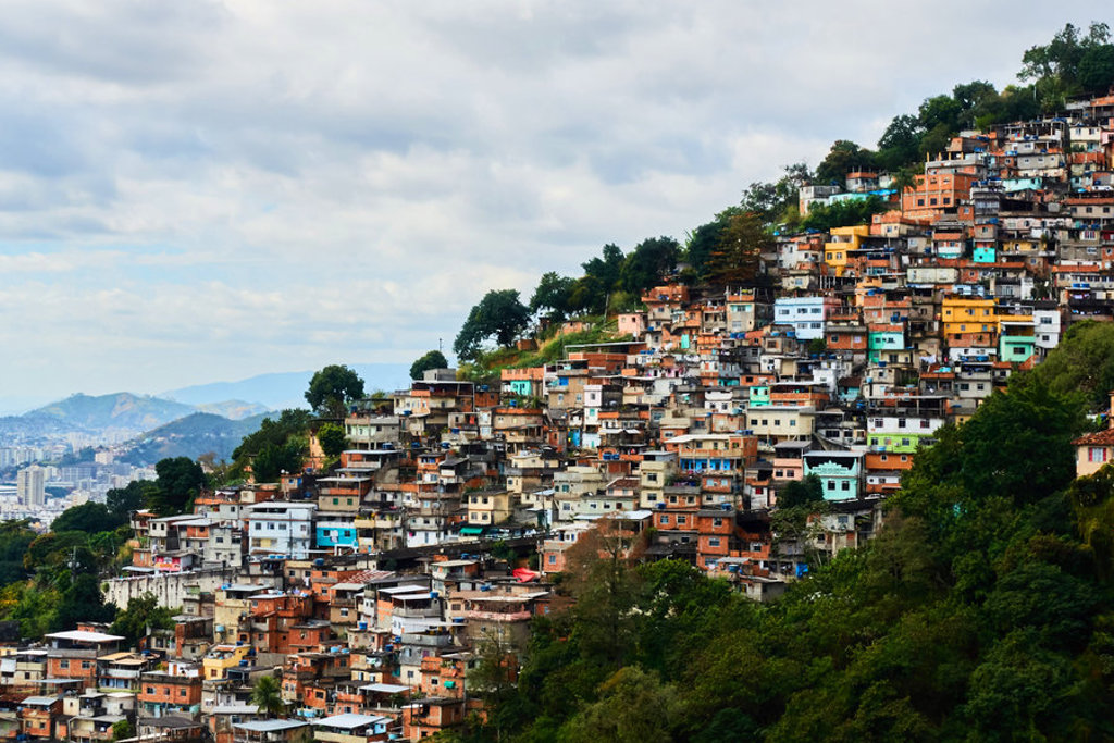 Gekleurde huizen op een heuvel in Rio de Janeiro, Brazilië, met groen eromheen en een bewolkte lucht.