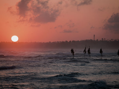 Steltvissers in zee bij zonsondergang aan de kust van Sri Lanka.