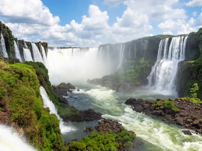 Panorama van de Iguazú-watervallen op de grens van Brazilië en Argentinië, met nevel boven de rivier.