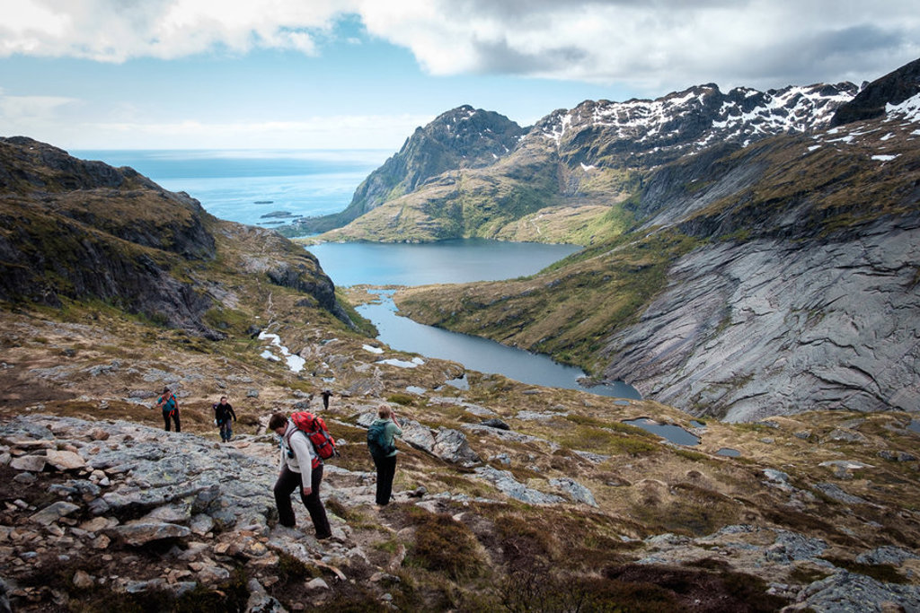 Wandelaars in berglandschap op de Lofoten, Noorwegen, met uitzicht op fjord en zee.