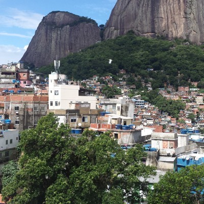 Uitzicht op de favela’s van Rio de Janeiro met kleurrijke huizen tegen een groene heuvel en rotsbergen.