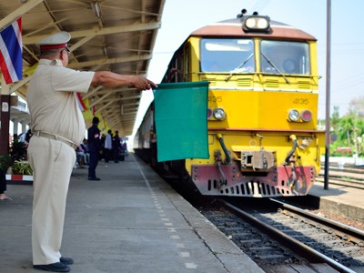 Stationschef met groene vlag bij aankomende trein op een station in Thailand, Route Thailand Noord en Zuid.
