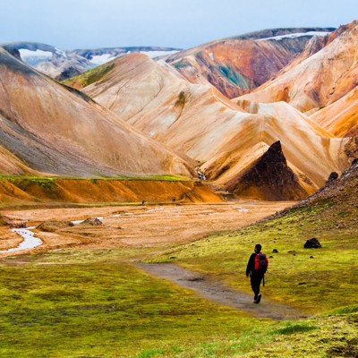 Wandelaar in Landmannalaugar met kleurrijke rhyolietbergen en lavaveld in IJsland.