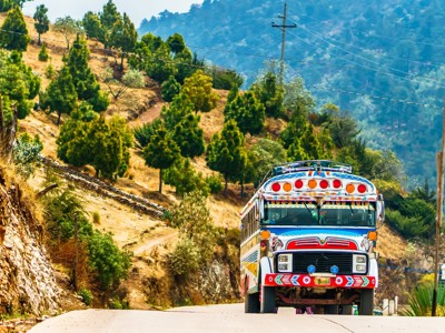 Kleurrijke bus op bergweg in Guatemala tijdens de route Guatemala, El Salvador en Honduras.