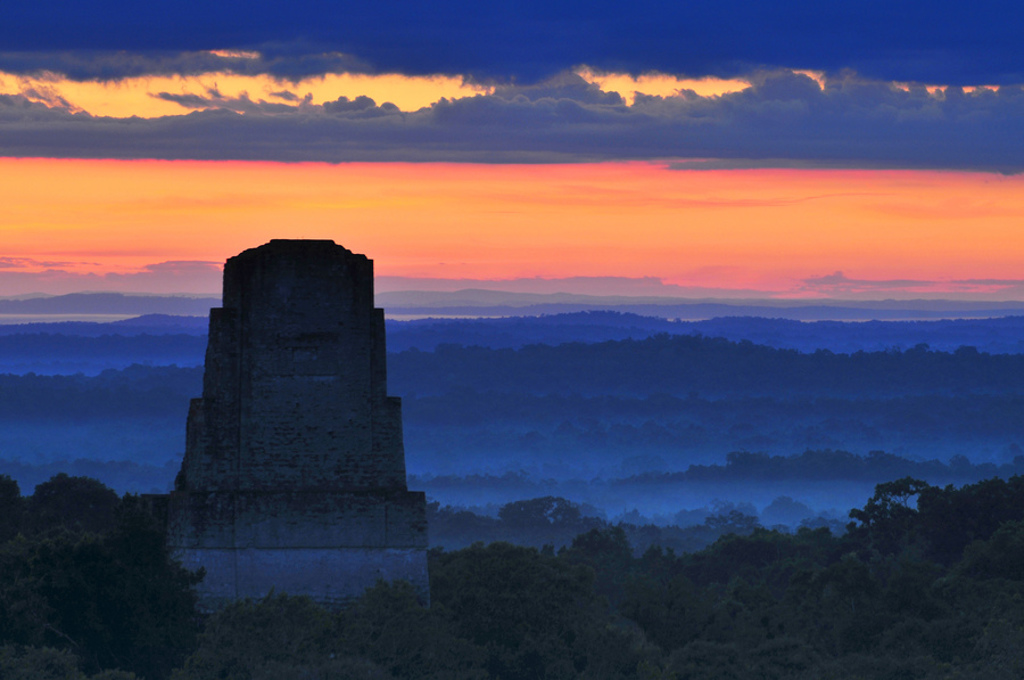 Zonsopkomst bij een Maya-tempel boven de jungle in Guatemala.