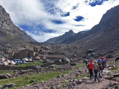 Wandelaars en muilezels op bergpad naar Mt. Toubkal, langs berghut en tentenkamp in de Atlas.