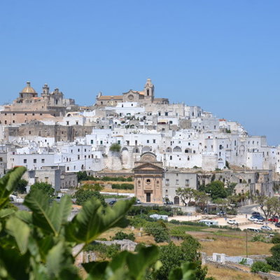 Witte huizen en kerken in Ostuni, Puglia, met uitzicht op het landschap tijdens een wandelvakantie in Italië.