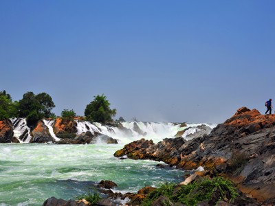 Watervallen en stroomversnellingen in de Mekong bij Laos en Cambodja, met wandelaar op rotsen.