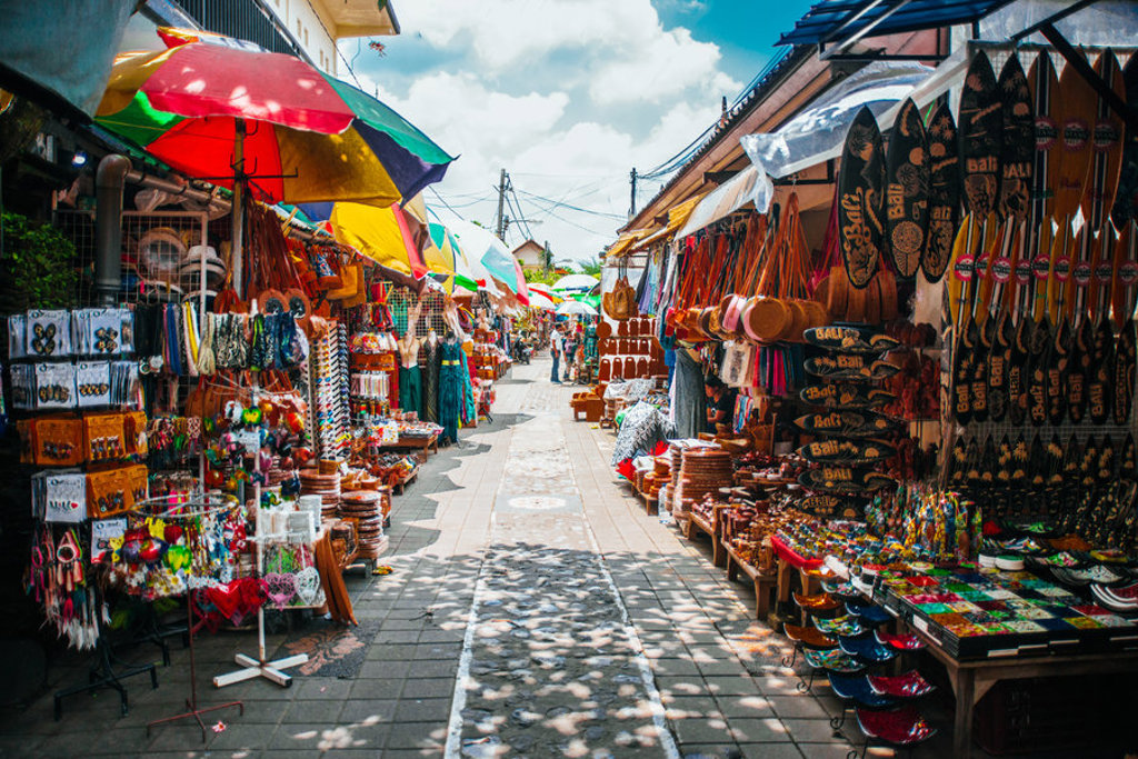 Kleurrijke marktstraat op Bali met souvenirwinkels, parasols en surfplanken langs de kraampjes.