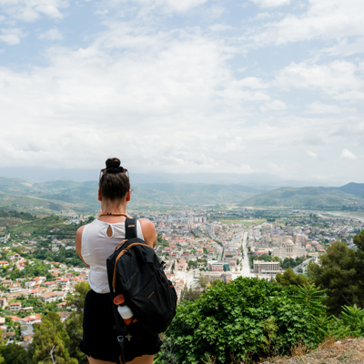 Wandelaar met rugzak kijkt uit over de stad Tirana en omliggende bergen in Albanië.
