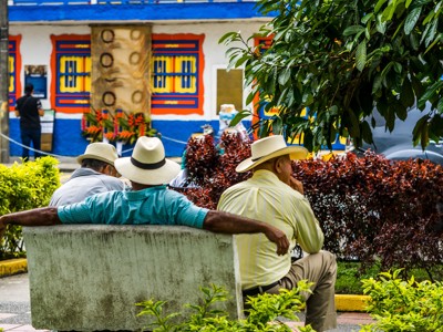 Mannen met hoeden op een bankje in een kleurrijk dorp in Colombia tijdens de Route Colombia.