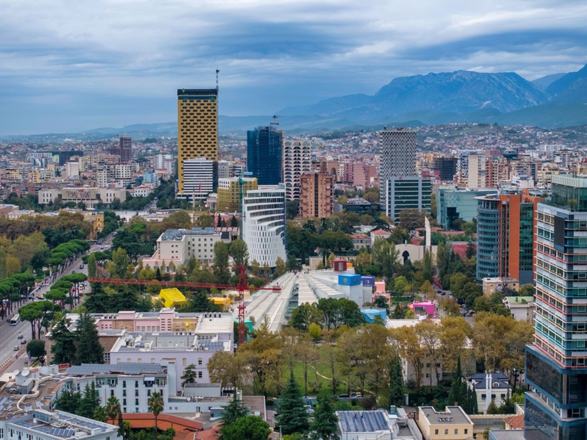 Skyline van Tirana met moderne hoogbouw en de bergen op de achtergrond.