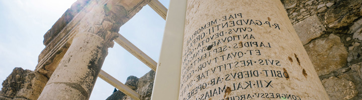 Oude zuilen en Romeinse inscriptie bij historische ruïnes in Israël.