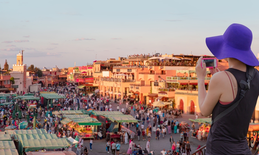 Toerist fotografeert het drukke plein Jemaa el-Fna en de markt in Marrakech tijdens een familiereis Marokko.