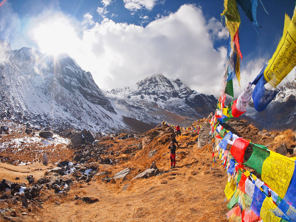 Wandelpad naar Annapurna Basecamp in Nepal met besneeuwde Himalaya-toppen en kleurrijke gebedsvlaggen.