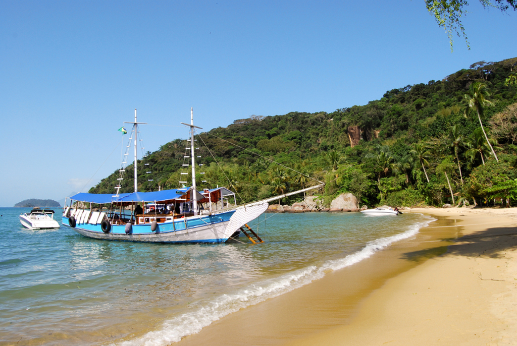 Boot voor anker bij een tropisch strand met groene heuvels in Brazilië tijdens een 22-35ers groepsrondreis.