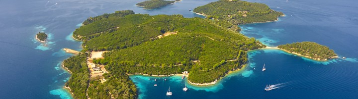 eiland Skorpios in Griekenland met groene heuvels, turquoise baaien en zeilboten.