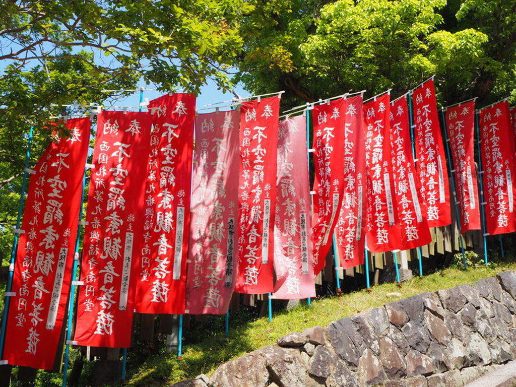 Rode Japanse tempelvlaggen met witte karakters langs een pad, tijdens een groepsrondreis Japan.