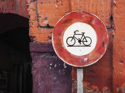 Verkeersbord met fietsverbod tegen een rode muur in Marokko.